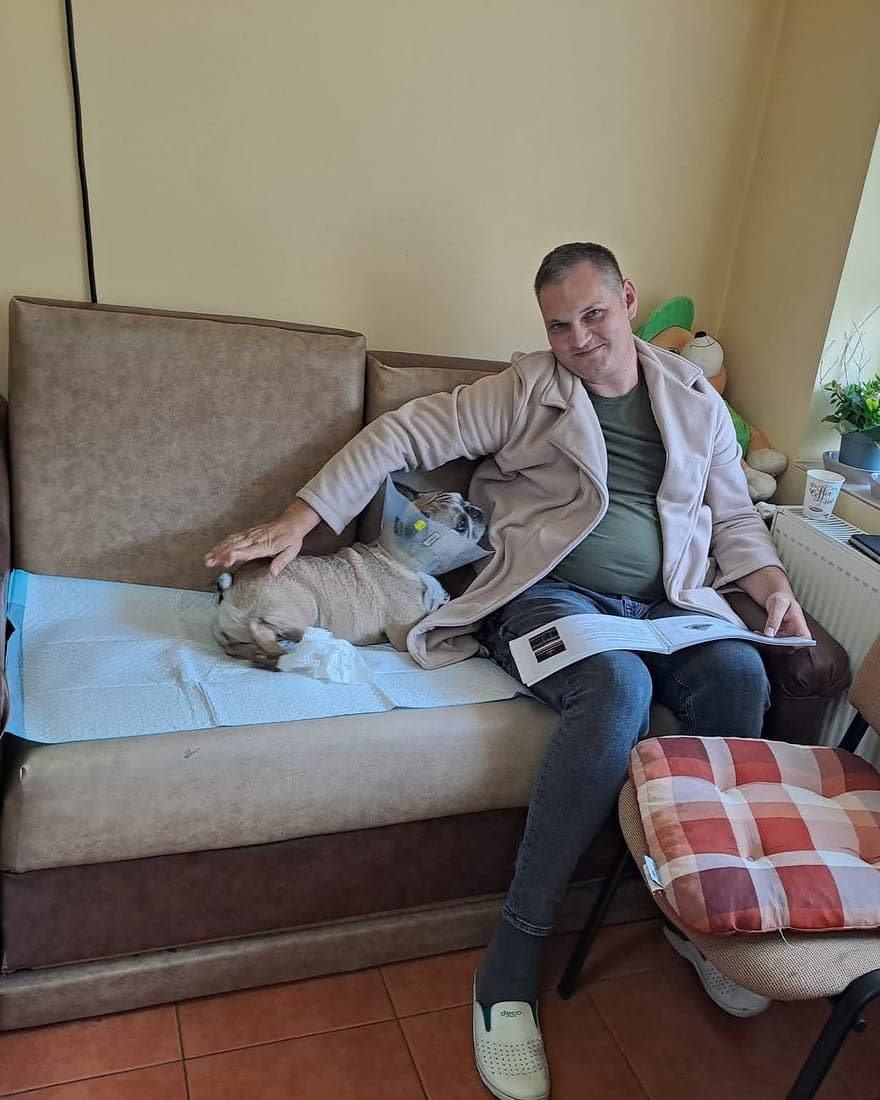 Un cățel alb odihnindu-se pe o pătură, pe canapeaua din sala de așteptare